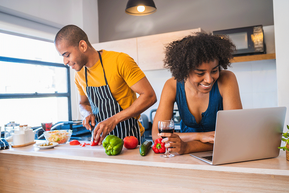 casal negro em uma cozinha seguindo uma receita do computador