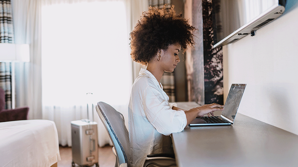 jovem negra sentada em uma escrivaninha e digitando em seu computador
